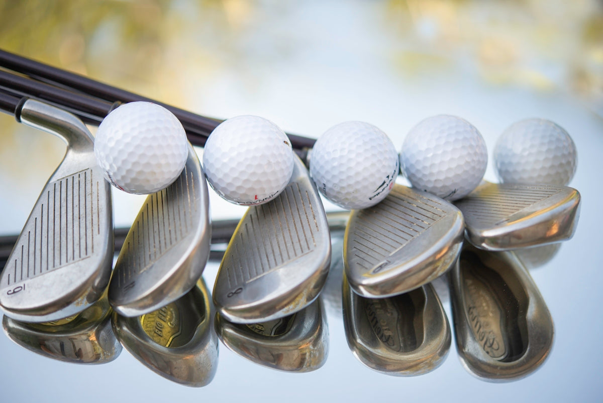 a group of golf balls and irons hanging from a rack