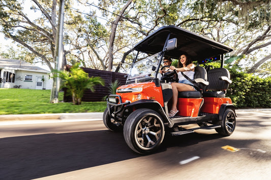 Two people riding in a golf cart on a street