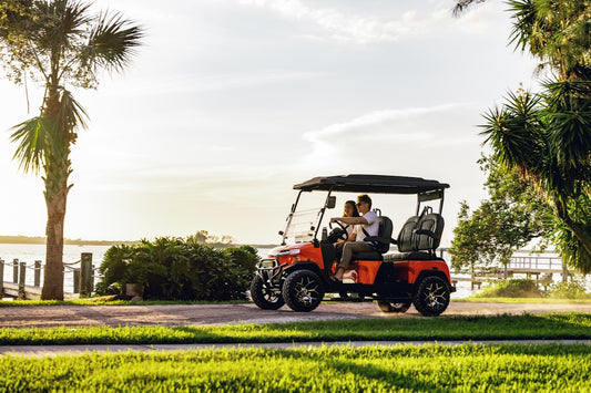 A man and a woman riding a red golf cart