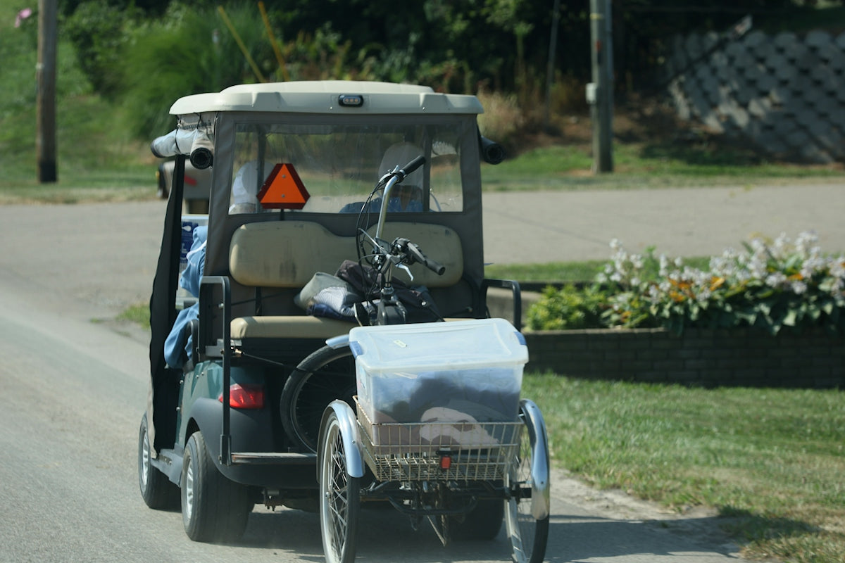 Golf cart carrying clubs and a trailer