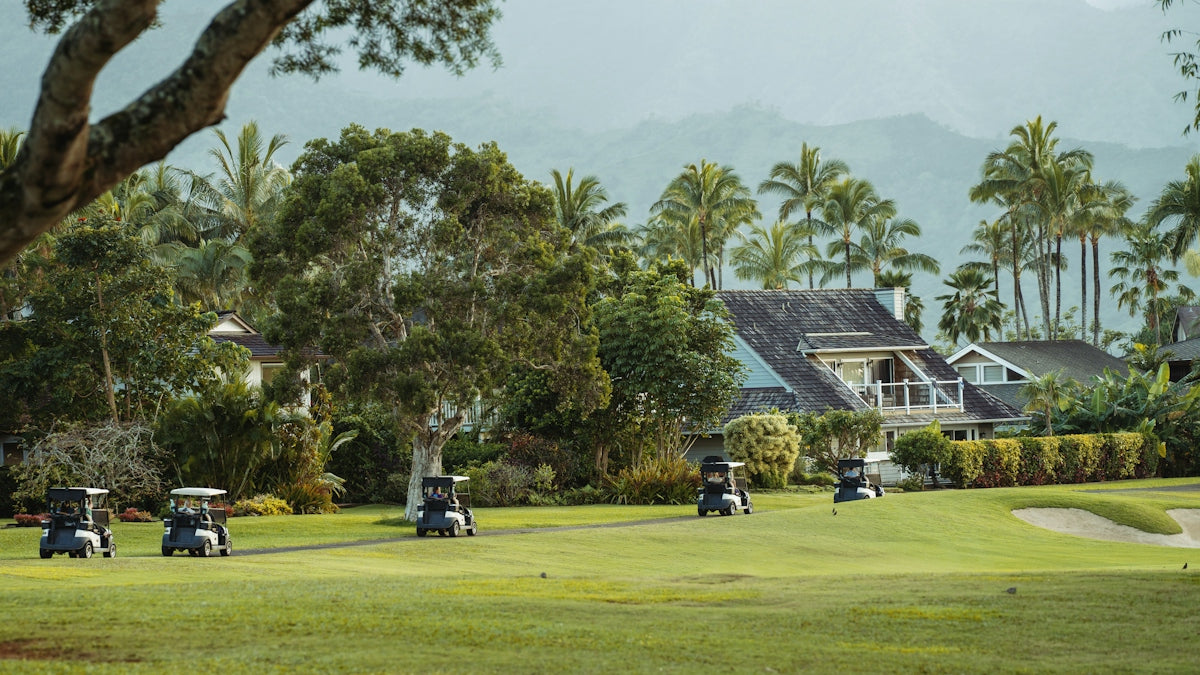 Golf carts on a lush green golf course with houses