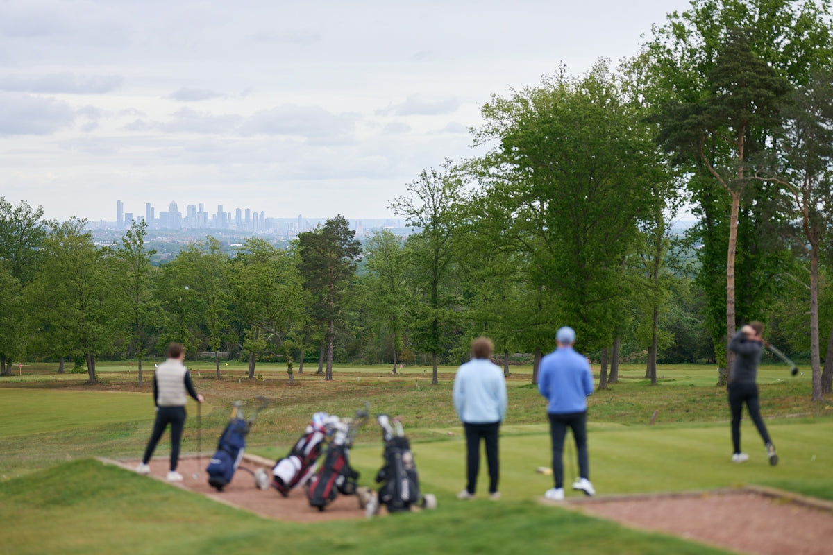 Golfers playing on a course with a distant city skyline