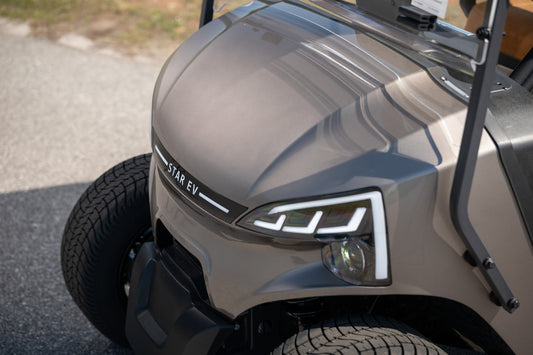A modern brown electric golf cart with unique headlights.