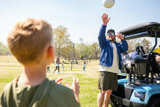 A man and boy playing volleyball near a golf cart