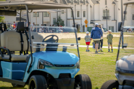 People walk past golf carts on a sunny course