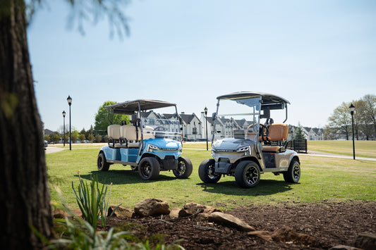 Two golf carts on a sunny green lawn.